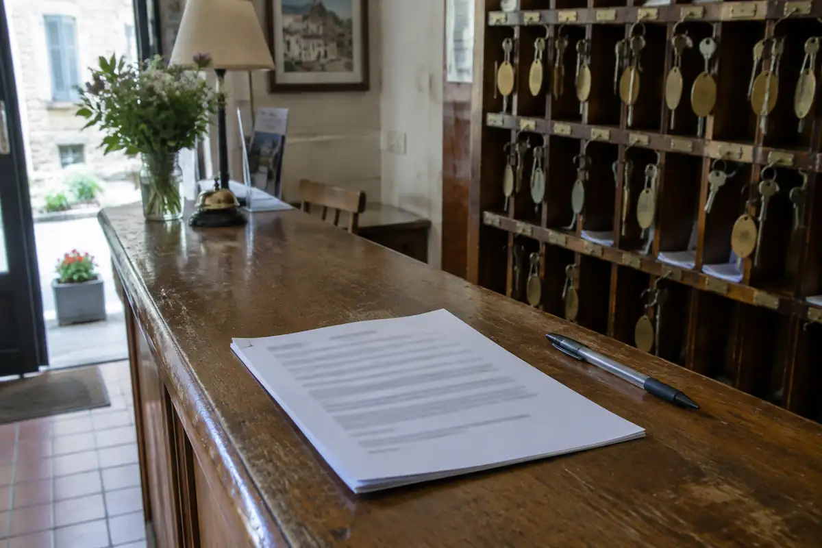 Contrat agrafé et stylo posés sur le comptoir d'une réception d'hôtel