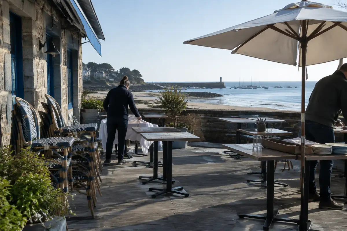 Terrasse de restaurant en début de saison avec chaises empilées et parasol à demi ouvert